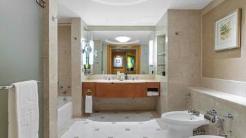 A modern bathroom with a large mirror, a bathtub, a sink, and a bidet.