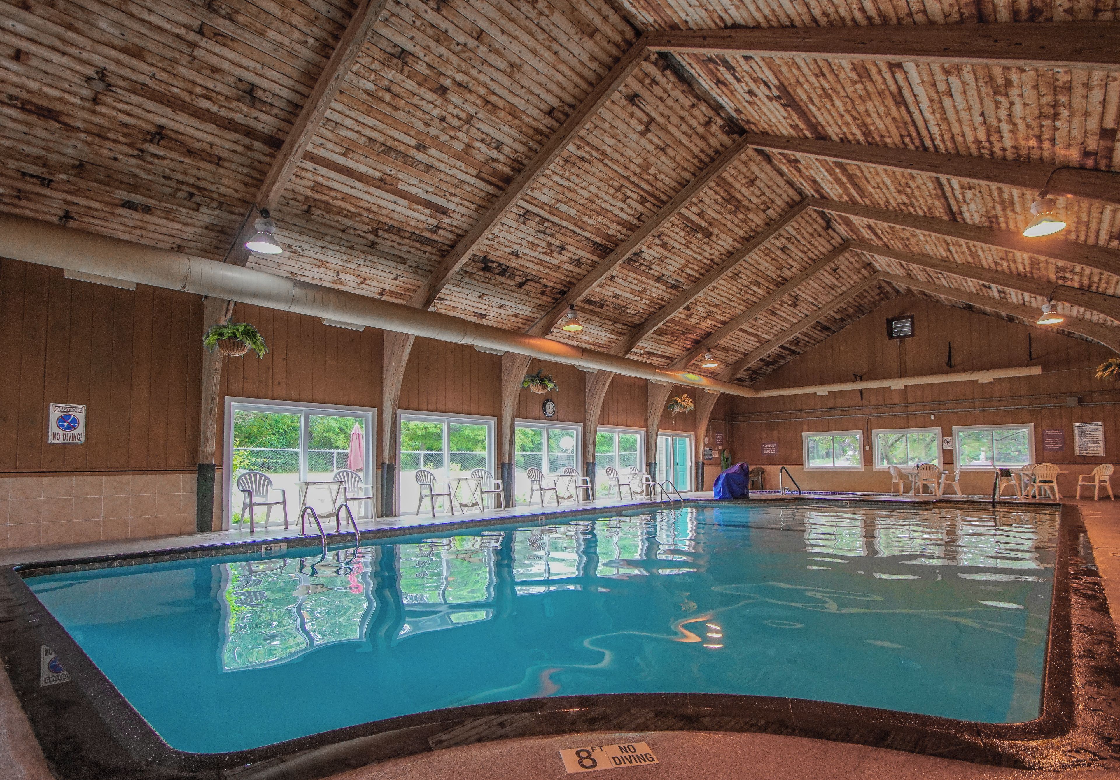 An indoor swimming pool with wooden beams on the ceiling, clear windows, and a 'NO DIVING' sign.
