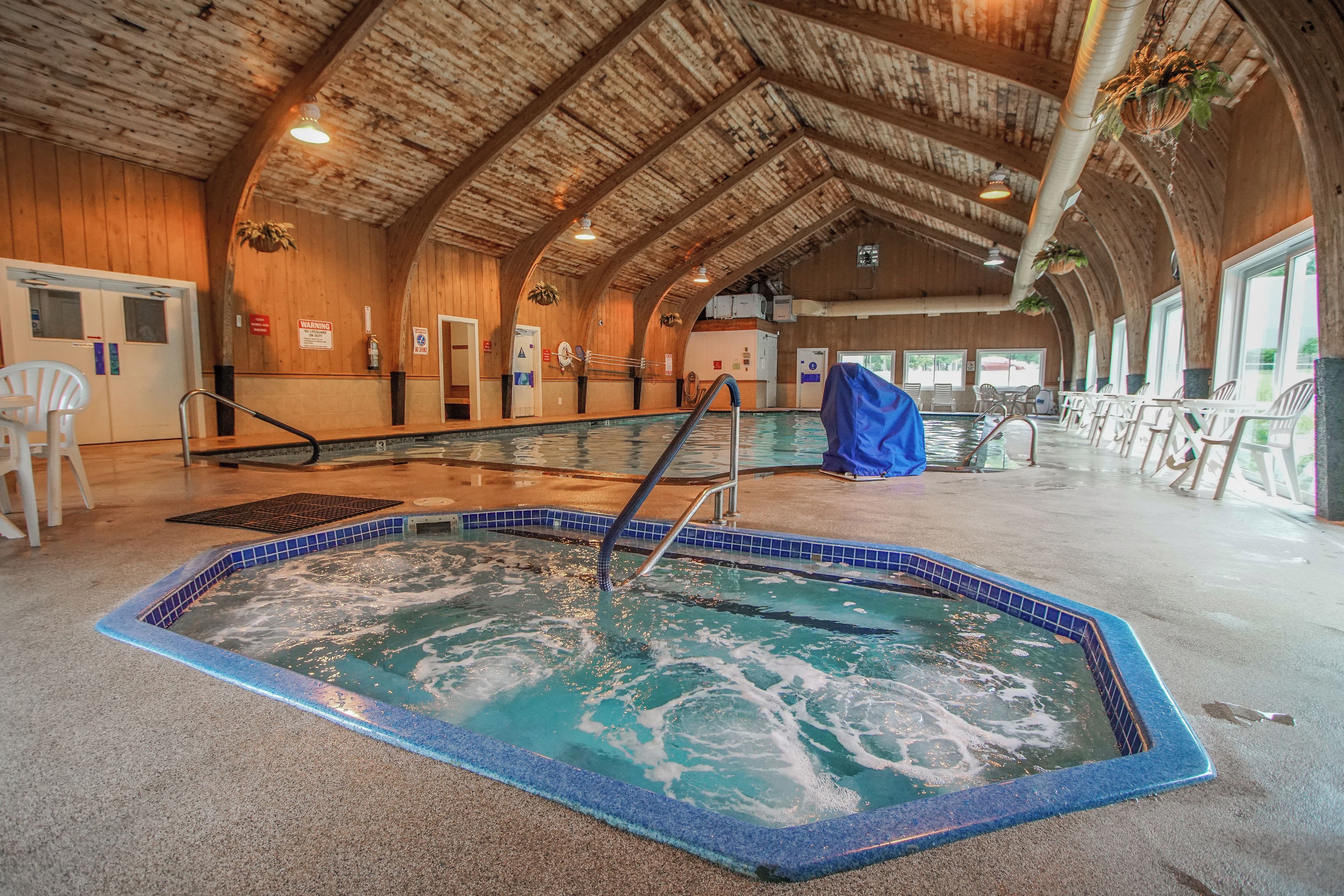 Une piscine intérieure avec un plafond en bois et un sol carrelé.