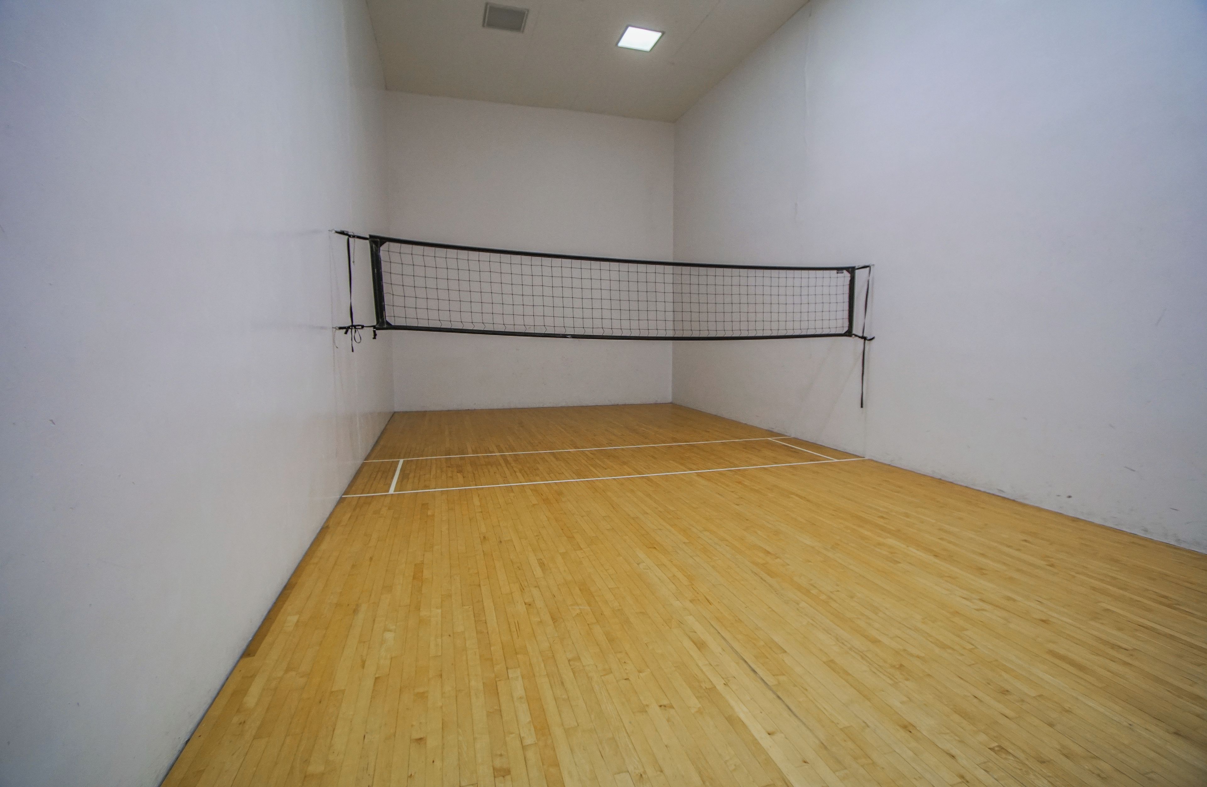 Ein Squashplatz mit Holzboden und Netz.