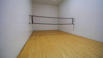 Ein Squashplatz mit Holzboden und Netz.