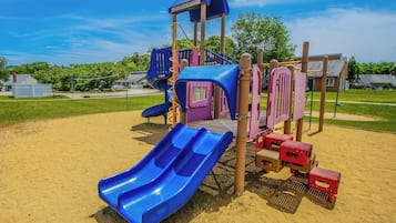 A playground with a blue slide, climbing structures, and a covered play area.