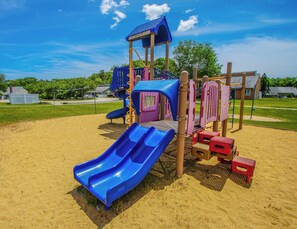 Un parque infantil con un tobogán azul, estructuras para escalar y una zona de juegos cubierta.