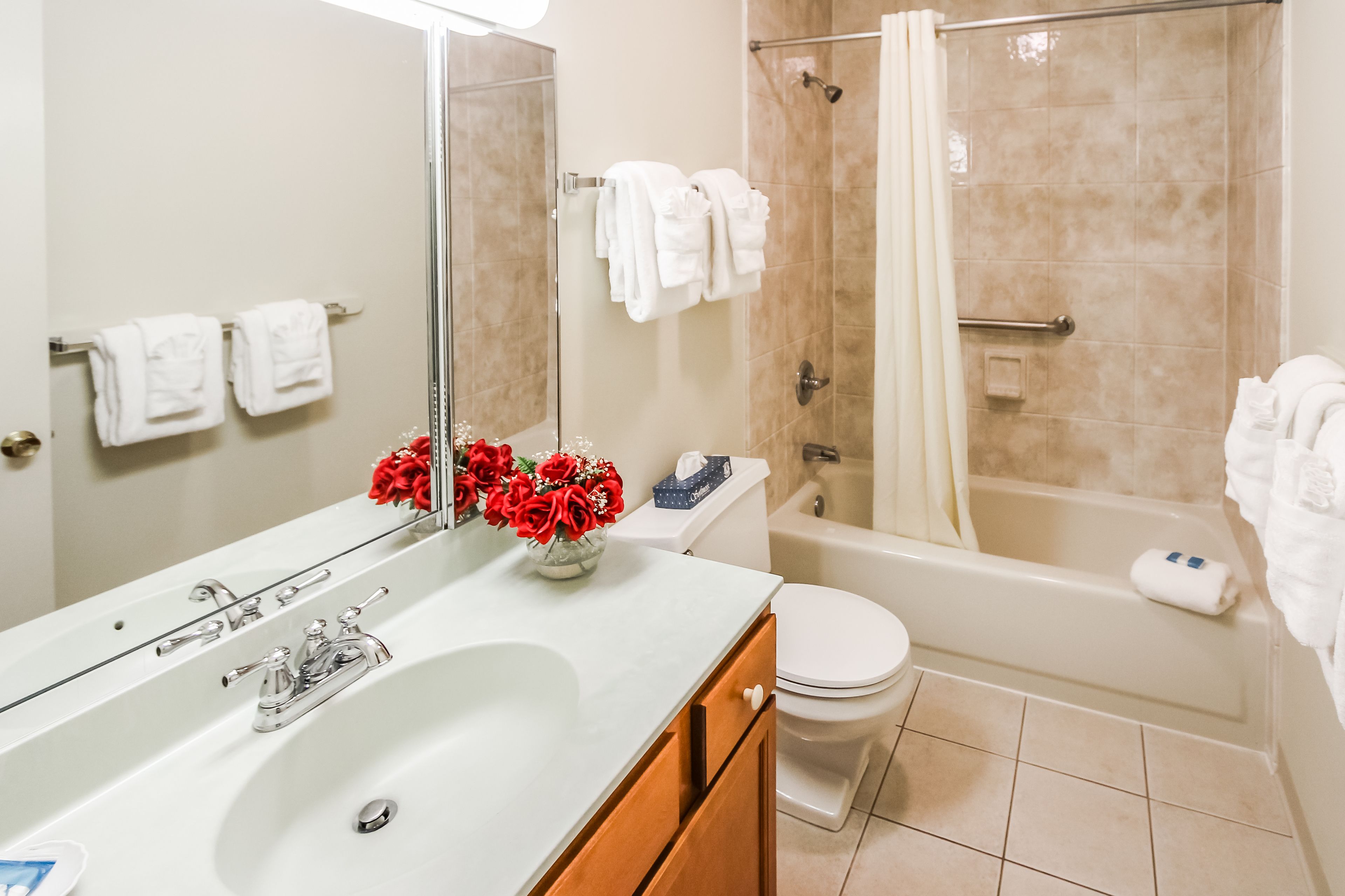 A bathroom with a sink, toilet, and bathtub. There are towels hanging on the wall and a shower curtain.