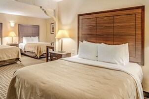 Habitación de hotel con dos camas, cada una con cabecero de madera, mesita de noche y lámpara.