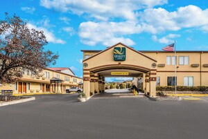 Entrada de hotel con un letrero que dice "Quality Inn" y una altura libre de 2.9 metros.