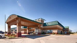 A hotel with a covered parking area, a green roof, and a central entrance.