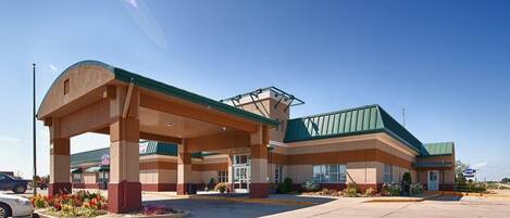 A hotel with a covered parking area, a green roof, and a central entrance.