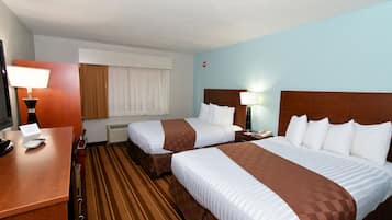 Habitación de hotel con dos camas, un escritorio con lámpara, teléfono y ventana con cortinas.