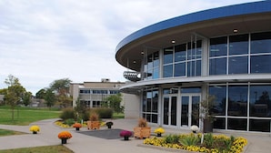 A modern building with large windows and a curved facade, surrounded by landscaped flower beds. - Rock Island Inn & Suites Marshalltown (Marshalltown)