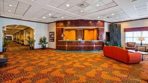 A hotel lobby with a reception desk, a red sofa, and a patterned carpet. - Rock Island Inn & Suites Marshalltown (Marshalltown)