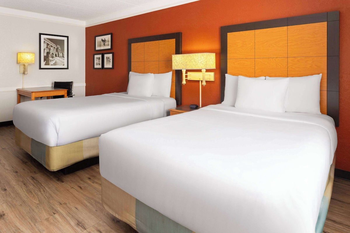 Une chambre d’hôtel avec deux lits, un bureau et une chaise.