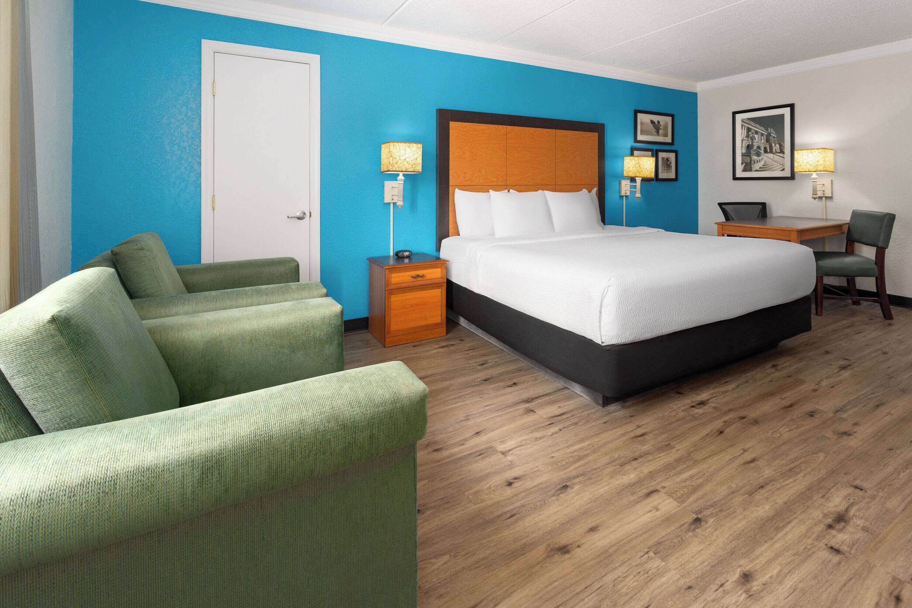 A hotel room with a large bed, a desk, a chair, and a couch.