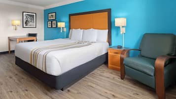 Una habitación de hotel con una cama grande, un escritorio, una silla y una mesita de noche.