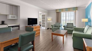 Et hotelværelse med spiseplads, fjernsyn, sofa og lampe.