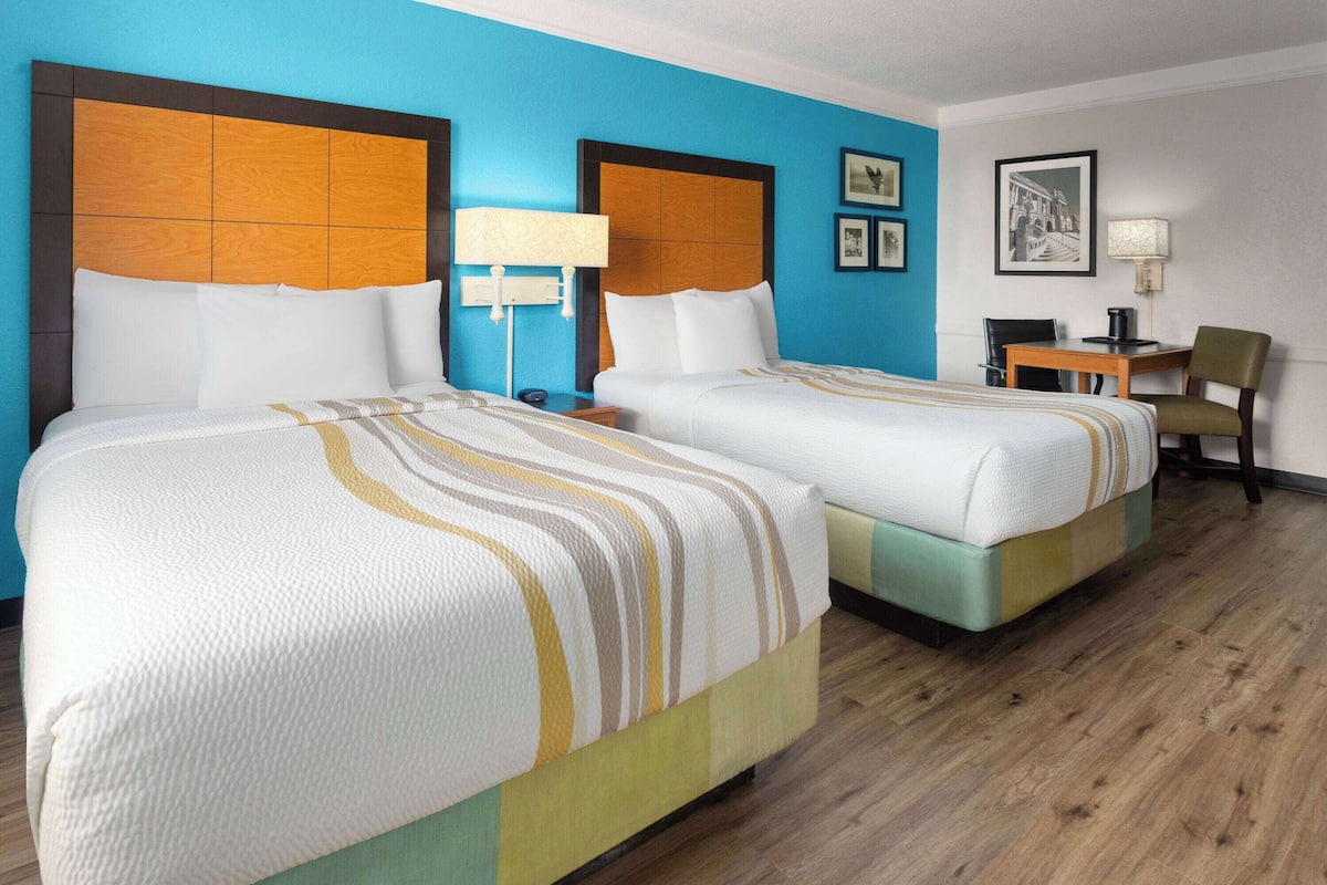 Une chambre d’hôtel avec deux lits, un bureau et une chaise.