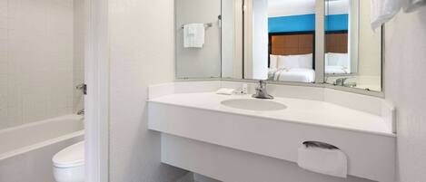 A modern bathroom with a white sink, a large mirror, and a bathtub.