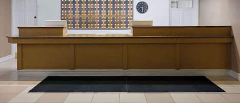 A reception desk with a patterned wall, a clock, and a tiled floor.