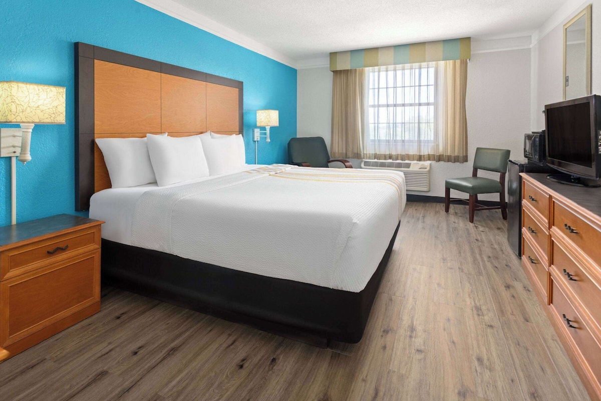 Une chambre d’hôtel avec un grand lit, une télévision, un bureau et une chaise.
