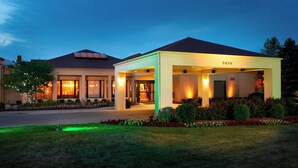 A hotel with a covered entrance, a well-maintained lawn, and a clear sky. - Courtyard by Marriott Rockford (Rockford)