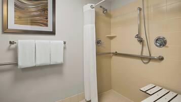 A shower area with a handrail, a white shower curtain, and a framed artwork on the wall.