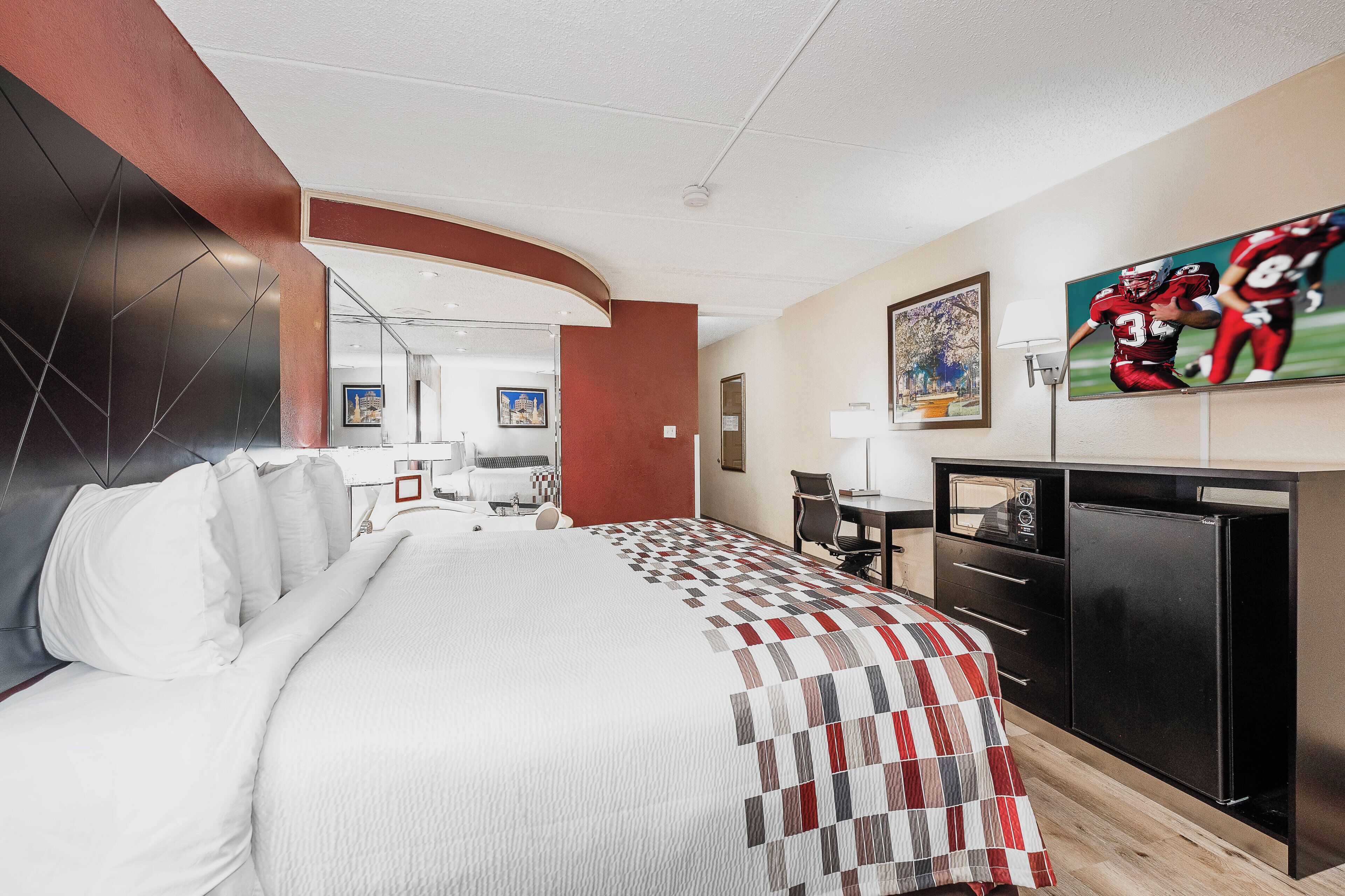 Une chambre d’hôtel équipée d’un lit, d’un bureau, d’une télévision et d’un réfrigérateur.