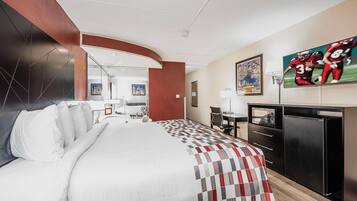 Une chambre d’hôtel équipée d’un lit, d’un bureau, d’une télévision et d’un réfrigérateur.