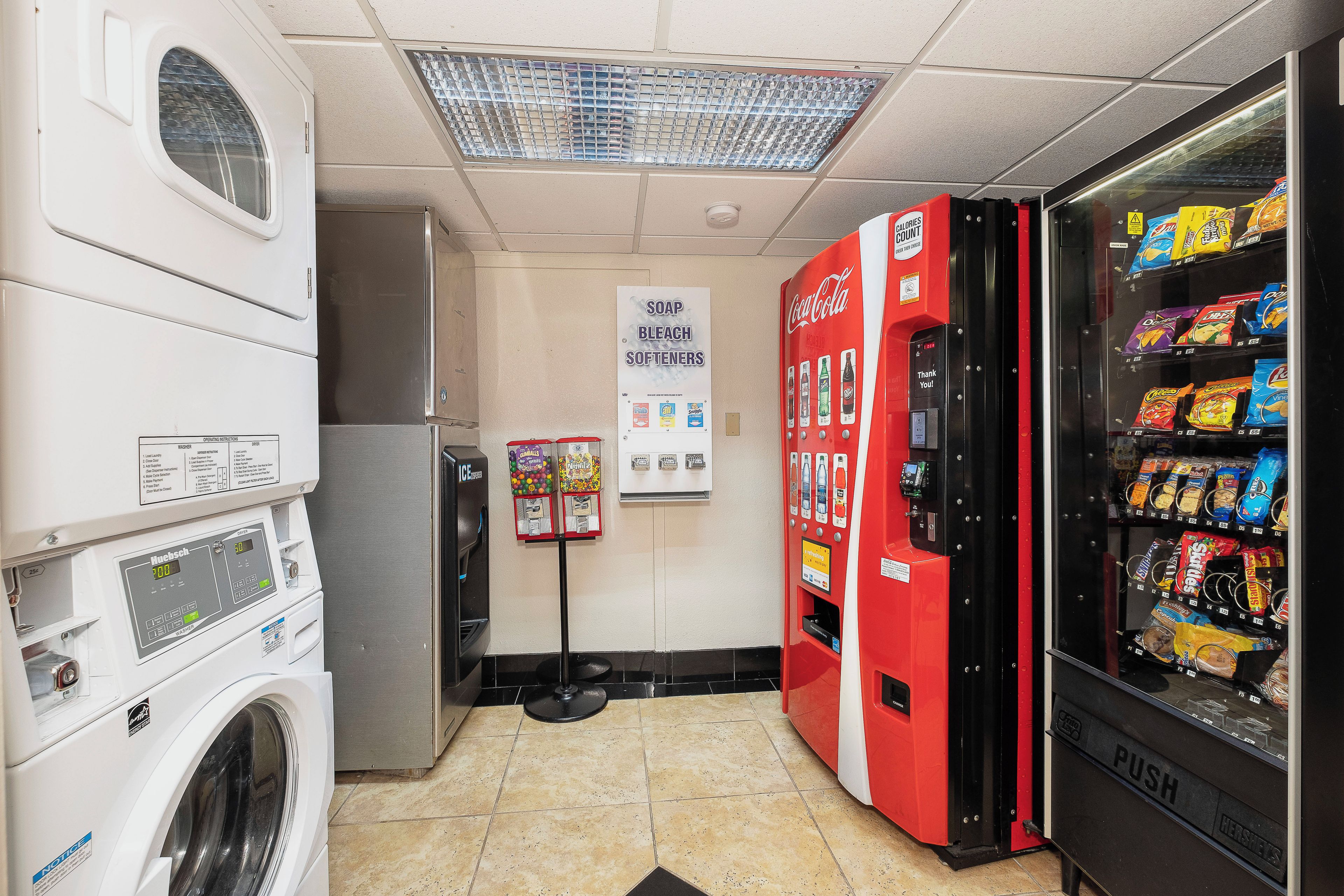 Une laverie équipée d’une machine à laver, d’un sèche-linge et d’un distributeur automatique de collations.