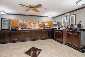 A hotel breakfast area with a self-serve station, a ceiling fan, and a tiled floor. - Red Roof Inn & Suites Macon (Macon)