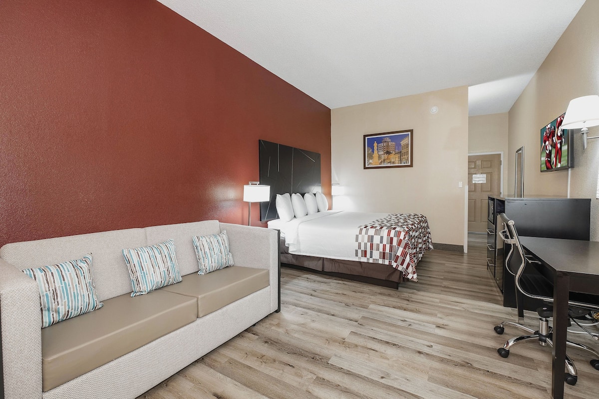 Una habitación de hotel con sofá, cama, escritorio y una silla.