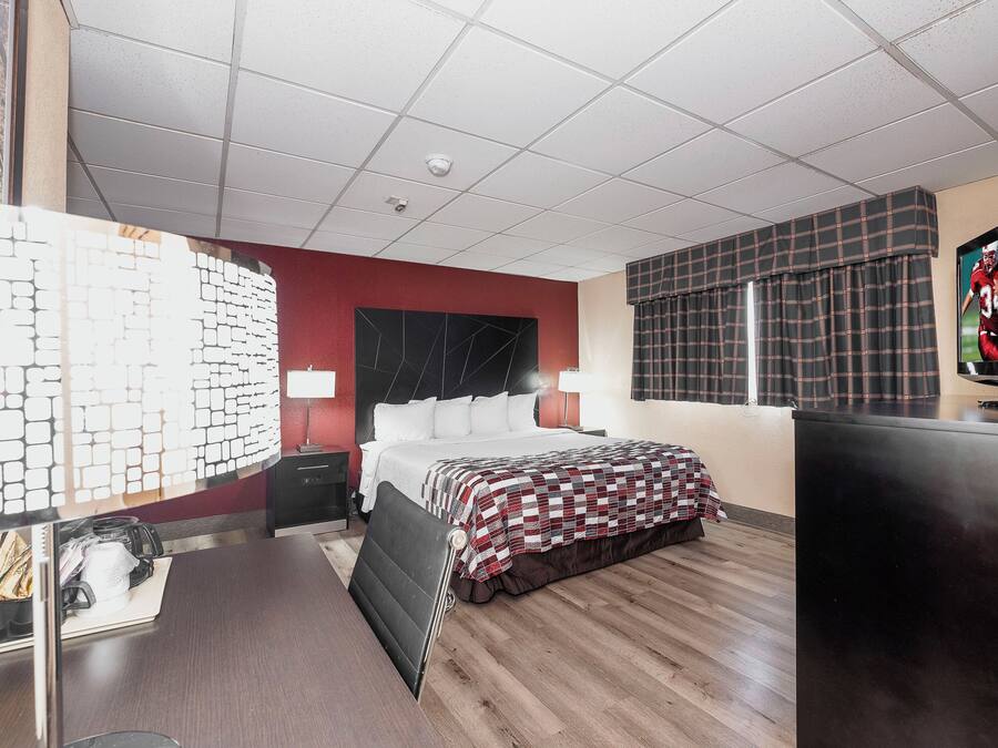 A hotel room with a bed, a desk, a television, and a window with curtains.