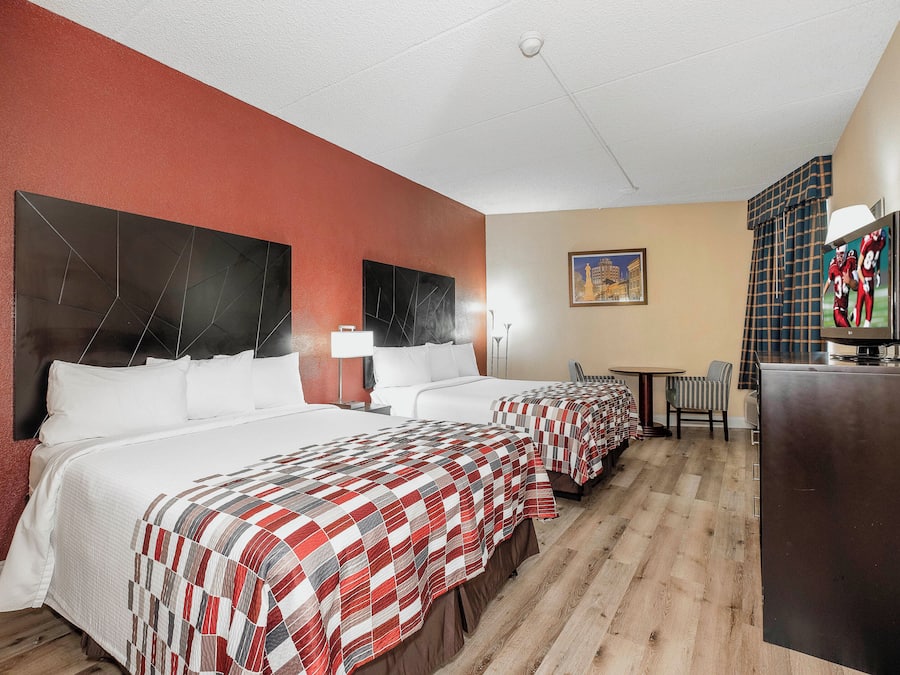 Hotellihuone, jossa on kaksi sänkyä, työpöytä, televisio ja taulu seinällä.