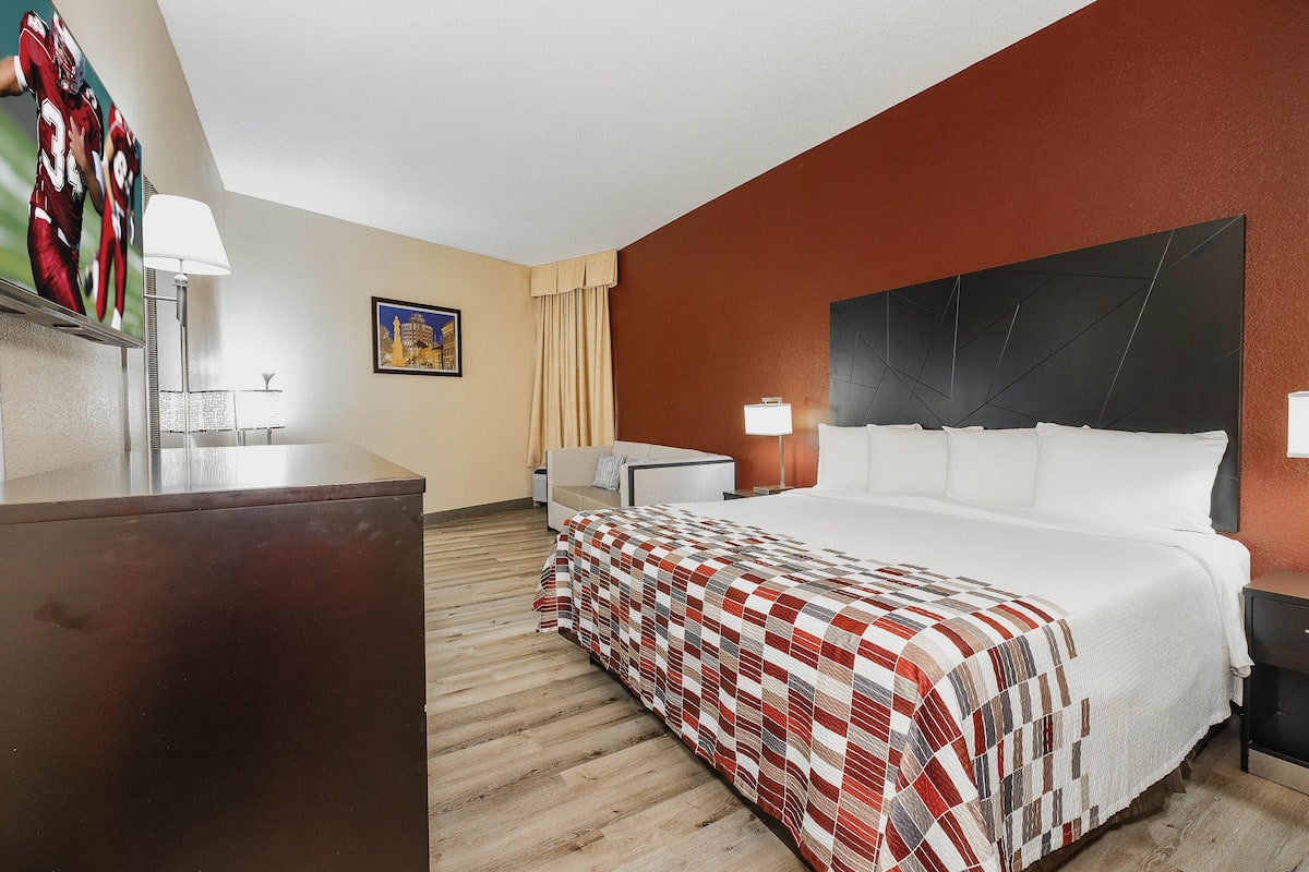 Una habitación de hotel con una cama grande, un escritorio, una silla y un televisor en la pared.