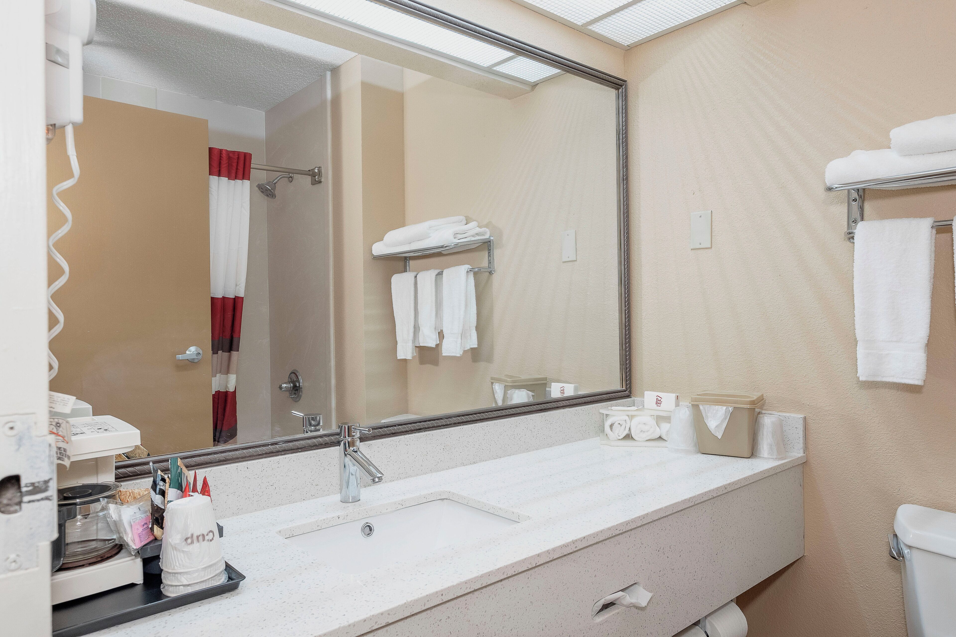 Une salle de bain avec un grand miroir, un lavabo, des toilettes et un espace douche.