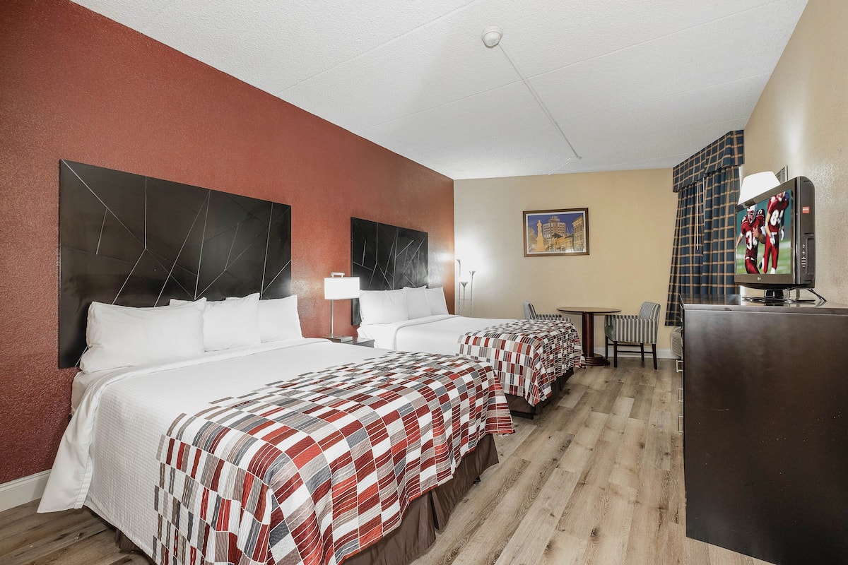 Habitación de hotel con dos camas, televisión, escritorio y una silla.