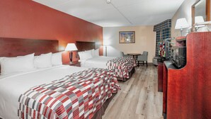 A hotel room with two beds, a desk, a television, and a painting on the wall. - Red Roof Inn & Suites Macon (Macon)
