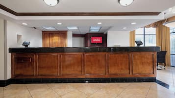 A reception desk with a flat-screen TV, wooden paneling, and a tiled floor.