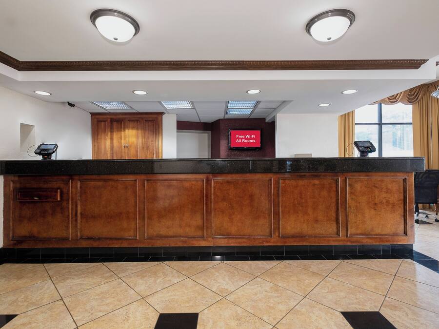 A reception desk with a flat-screen TV, wooden paneling, and a tiled floor.