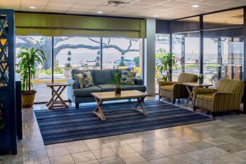 A lobby with a glass partition, seating area, and a view of the outside. at Quality Inn Biloxi Beach