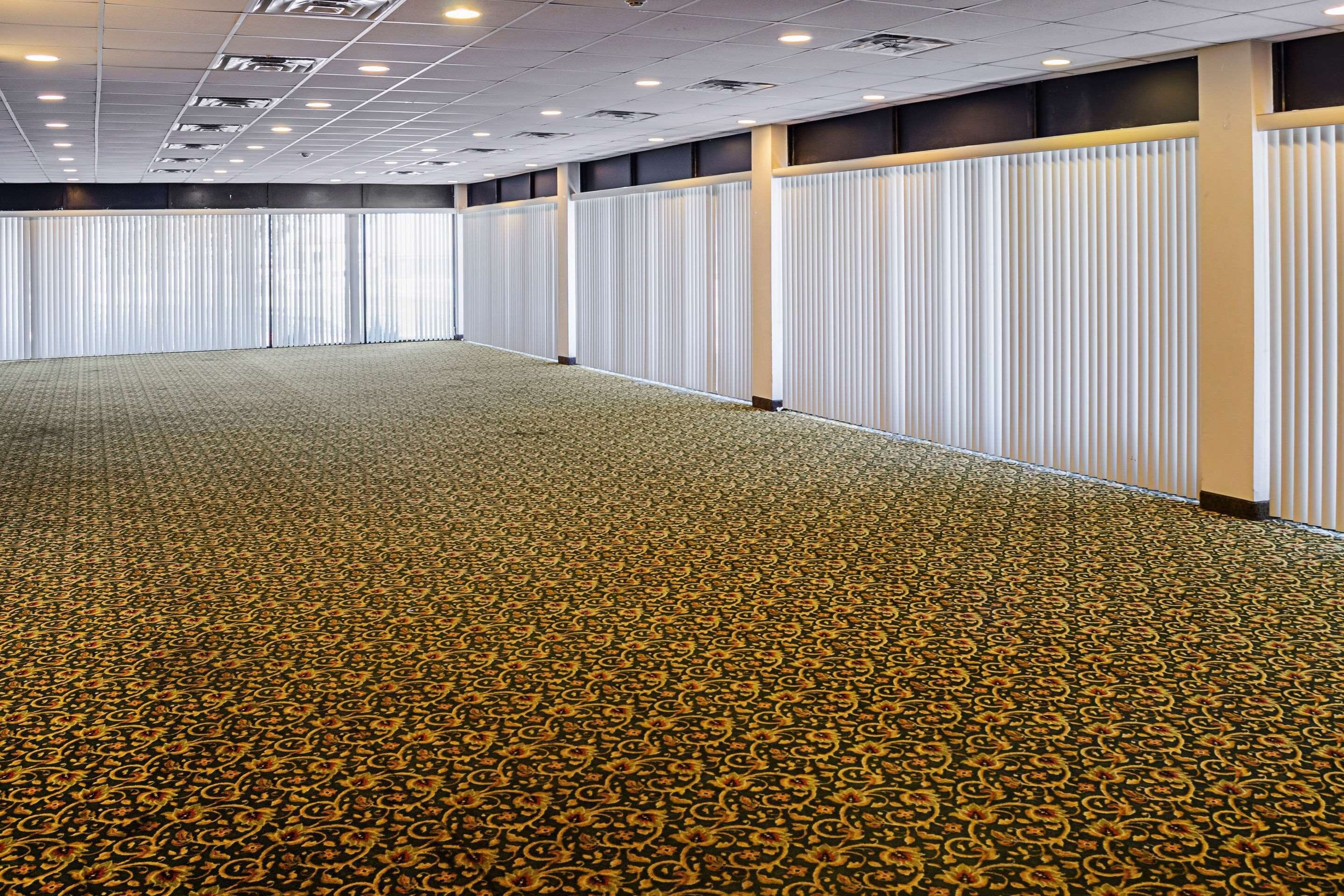 Una grande sala conferenze con una moquette a motivi, pareti divisorie bianche e un soffitto con illuminazione a incasso.
