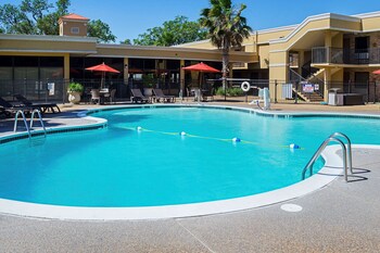 A Quality Inn with a red umbrella, picnic tables, and a brick wall. at Quality Inn Biloxi Beach