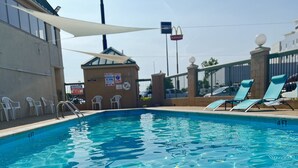 Una piscina con agua cristalina, sillas de descanso y un letrero de Days Inn.
