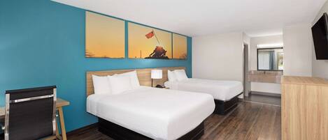 Une chambre d’hôtel avec deux lits, un bureau, une chaise, une télévision et un tableau au mur.