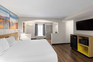 Een hotelkamer met een groot bed, een flatscreen televisie, een magnetron en een kleine kitchenette.