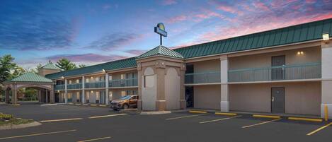 A motel with a green roof, a sign indicating it's a Days Inn, and a parking lot with marked spaces.