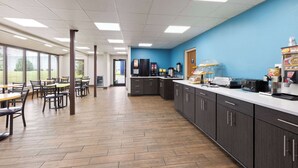 Una amplia cafetería con suelo de madera, una pared azul de acento y una larga barra con equipo para servicio de alimentos.