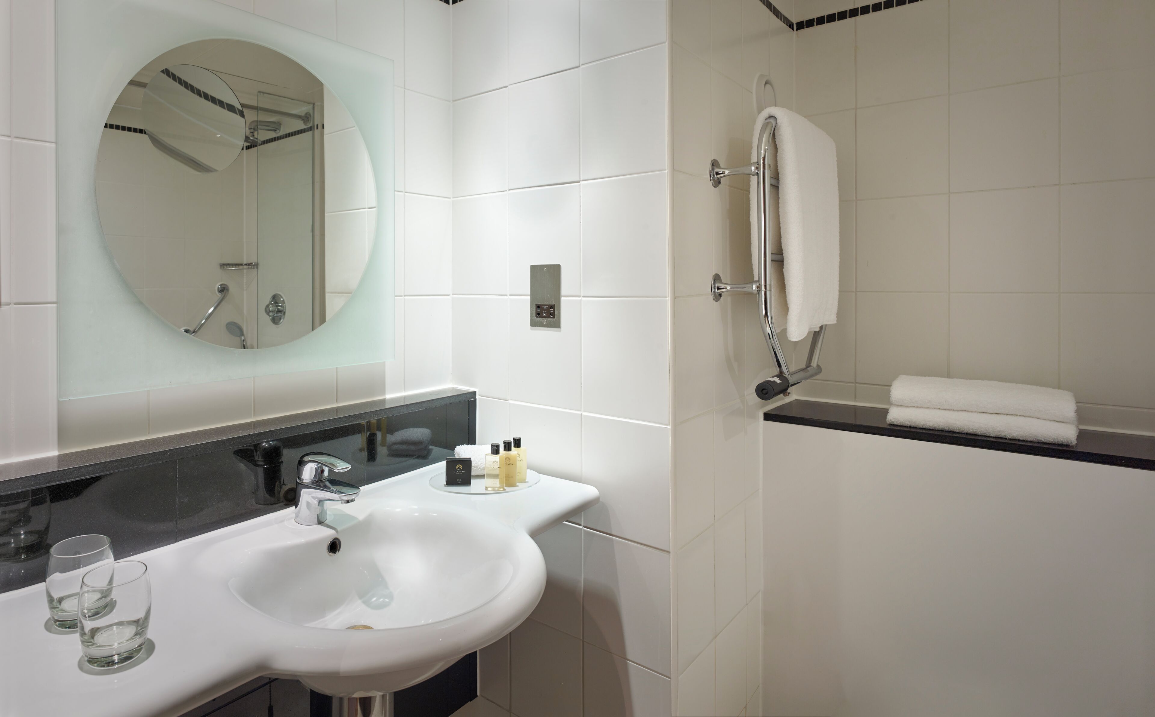A bathroom with a white sink, mirror, and shower.