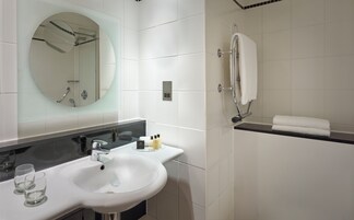 A bathroom with a white sink, mirror, and shower.