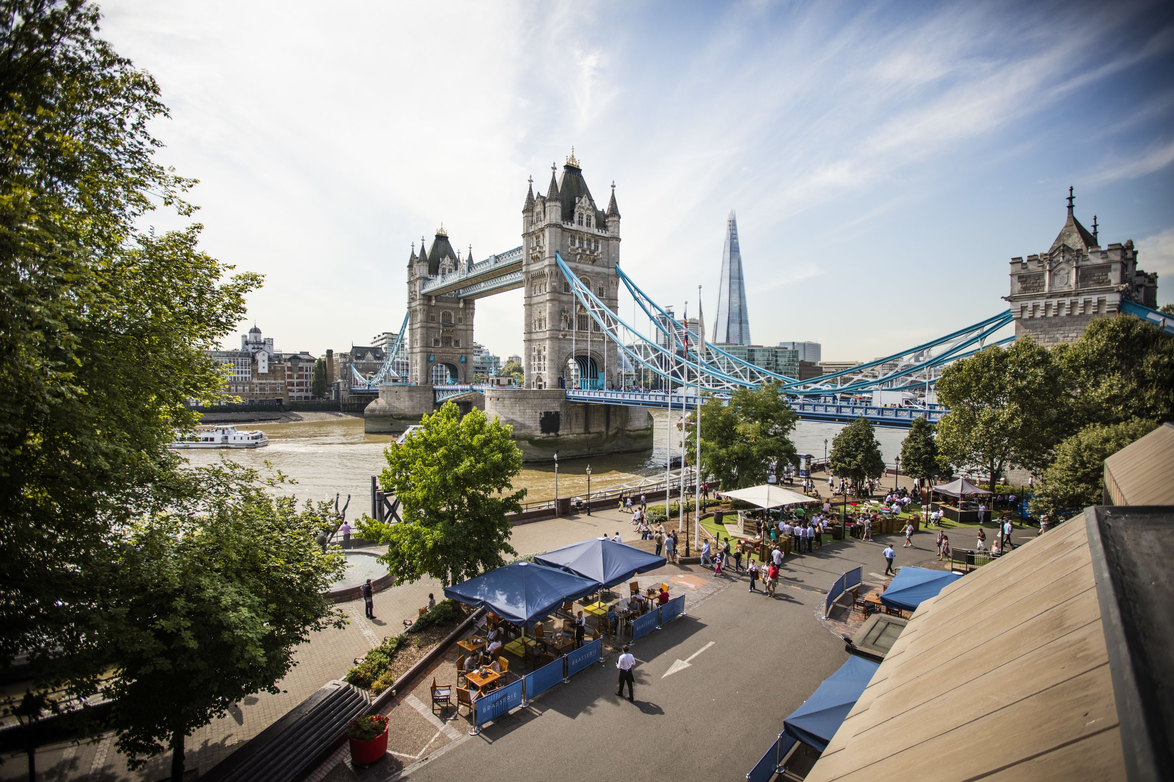 A view of Tower Bridge with a riverside market area in the foreground.
