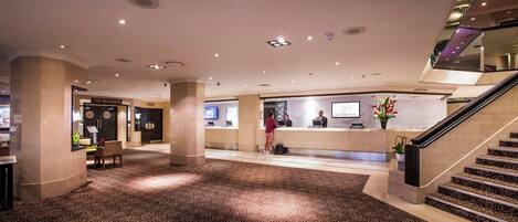 A hotel lobby with a reception desk, a staircase, and a restaurant named 'The Brasserie'.